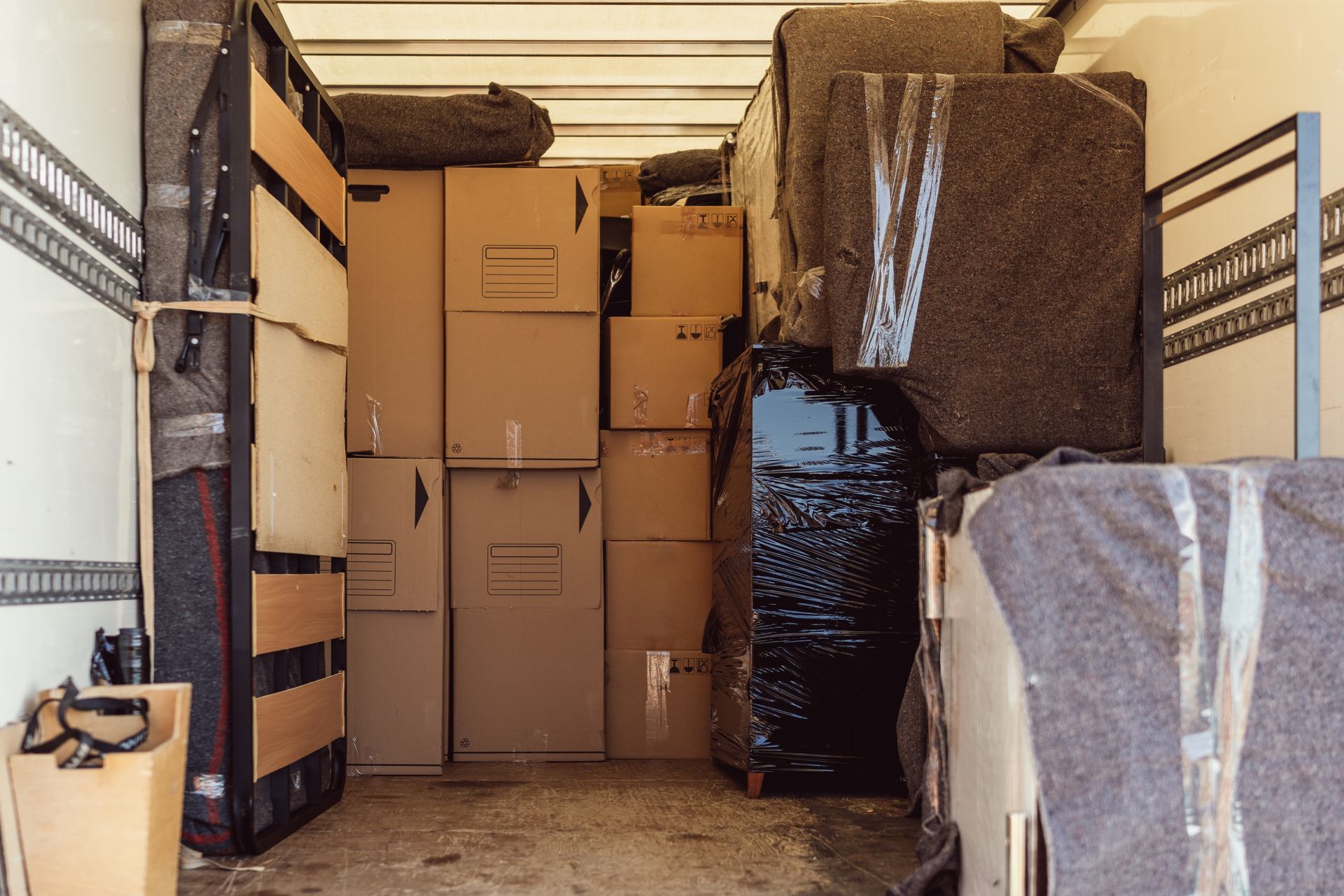 The inside of a moving truck filled with boxes and furniture.